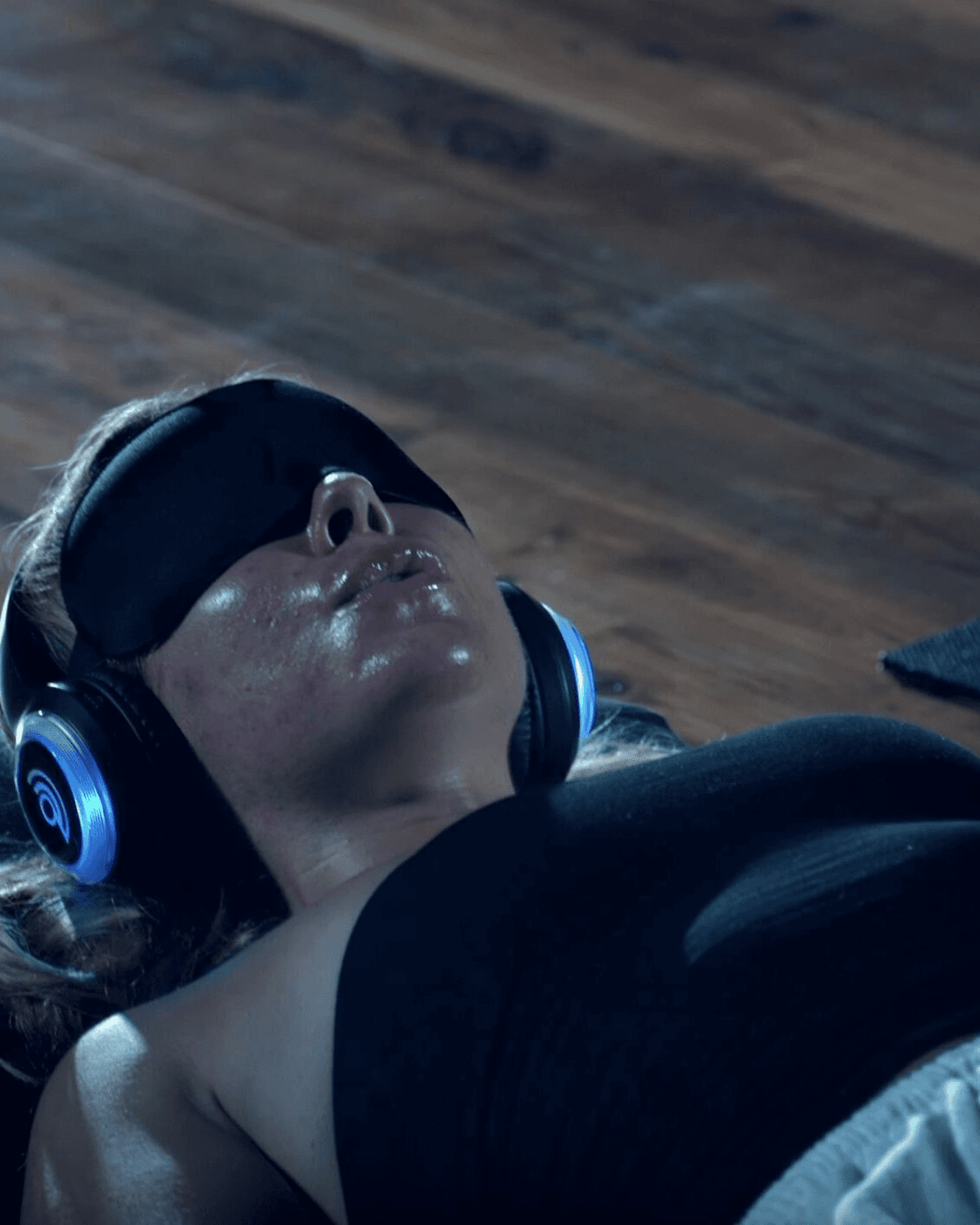 Brooke Stevenson facilitating a breathwork session, hands gently guiding a participant lying down with headphones