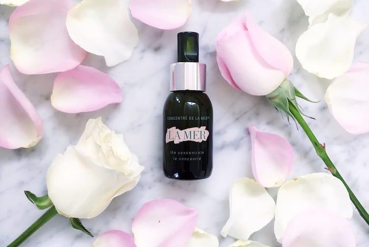 La Mer The Concentrate in deep green glass bottle displayed with skincare products on marble surface