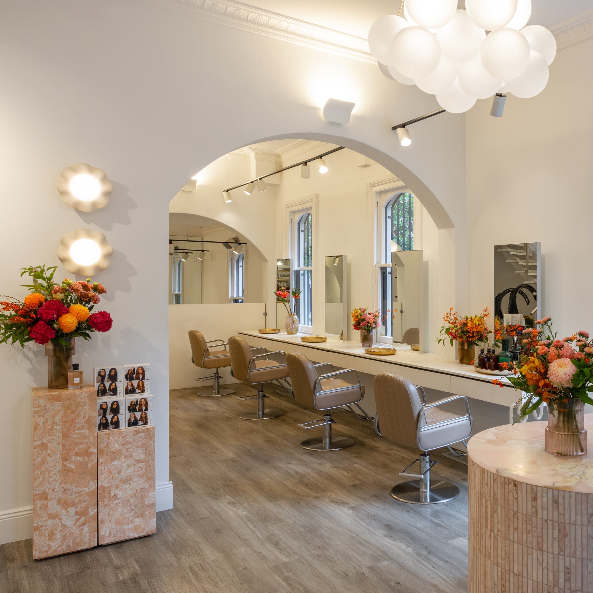 Bixie Colour Surry Hills salon interior with arched doorways, styling chairs, globe pendant lighting and fresh floral arrangements