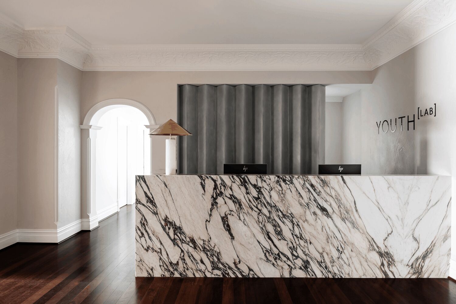 Modern luxury skincare clinic interior with marble fixtures, brass fittings, and contemporary art installation