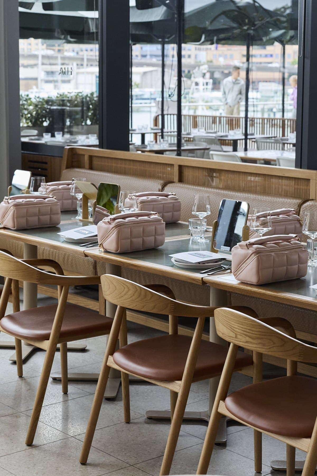 The table at Lua set with pink quilted makeup bags, glasses and a window view over Sydney Fish Market