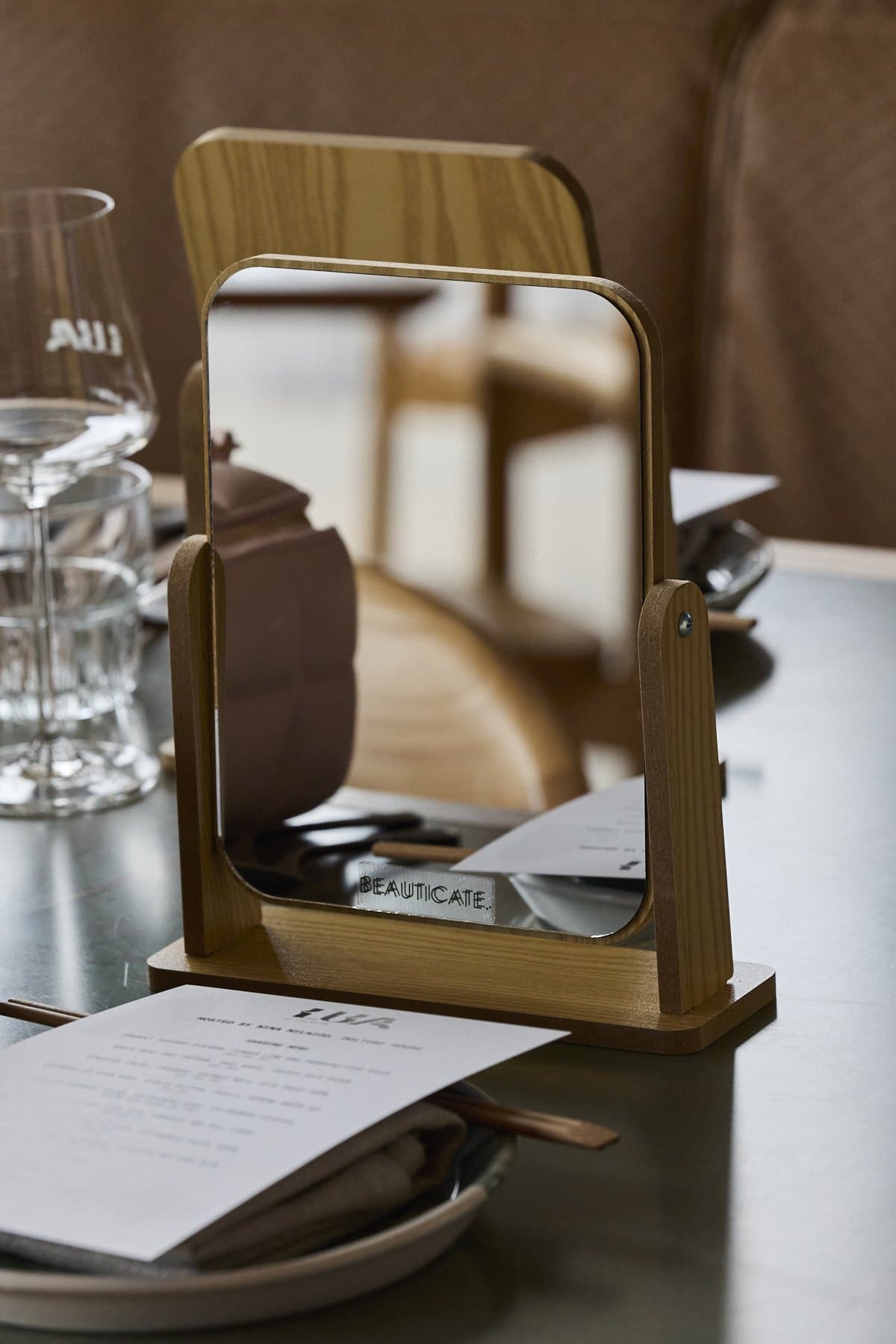 A small mirror and menu at a place setting on the table at Lua