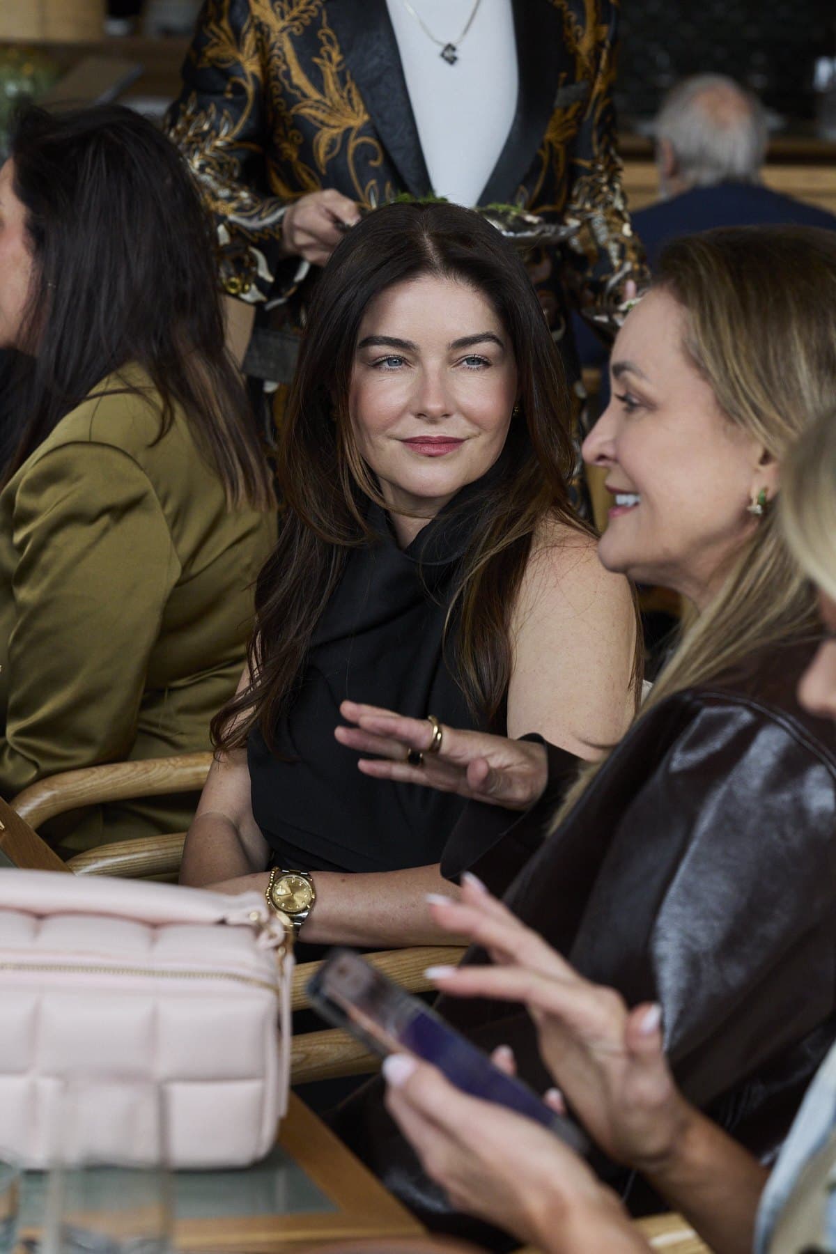 Two guests in conversation at the table at Lua, a pink bag in the foreground