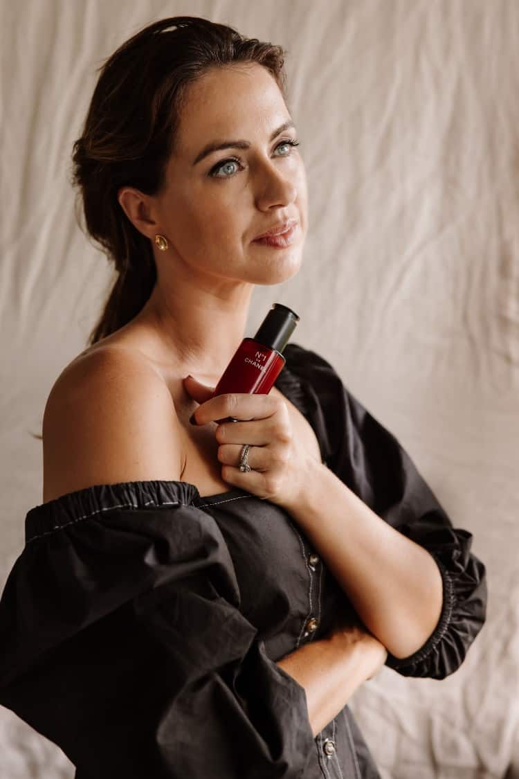 Sigourney Cantelo holding the No 1 de Chanel Revitalising Serum in a black off-shoulder top