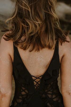 Sigourney Cantelo standing with confident posture at the beach in a black swimsuit