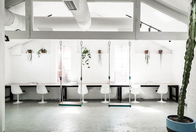 Teal ceiling-hung swings, white tulip chairs and hanging plants at Edwards and Co Melbourne