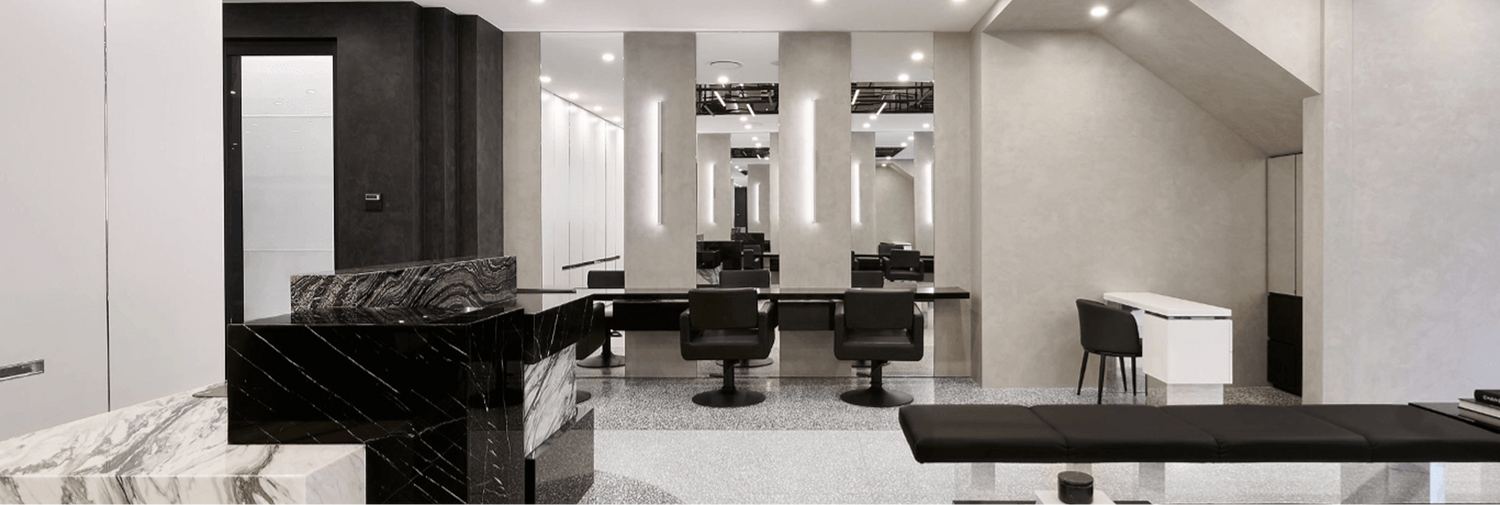 The Joh Bailey salon interior in Double Bay, with black marble reception desk and mirrored styling stations