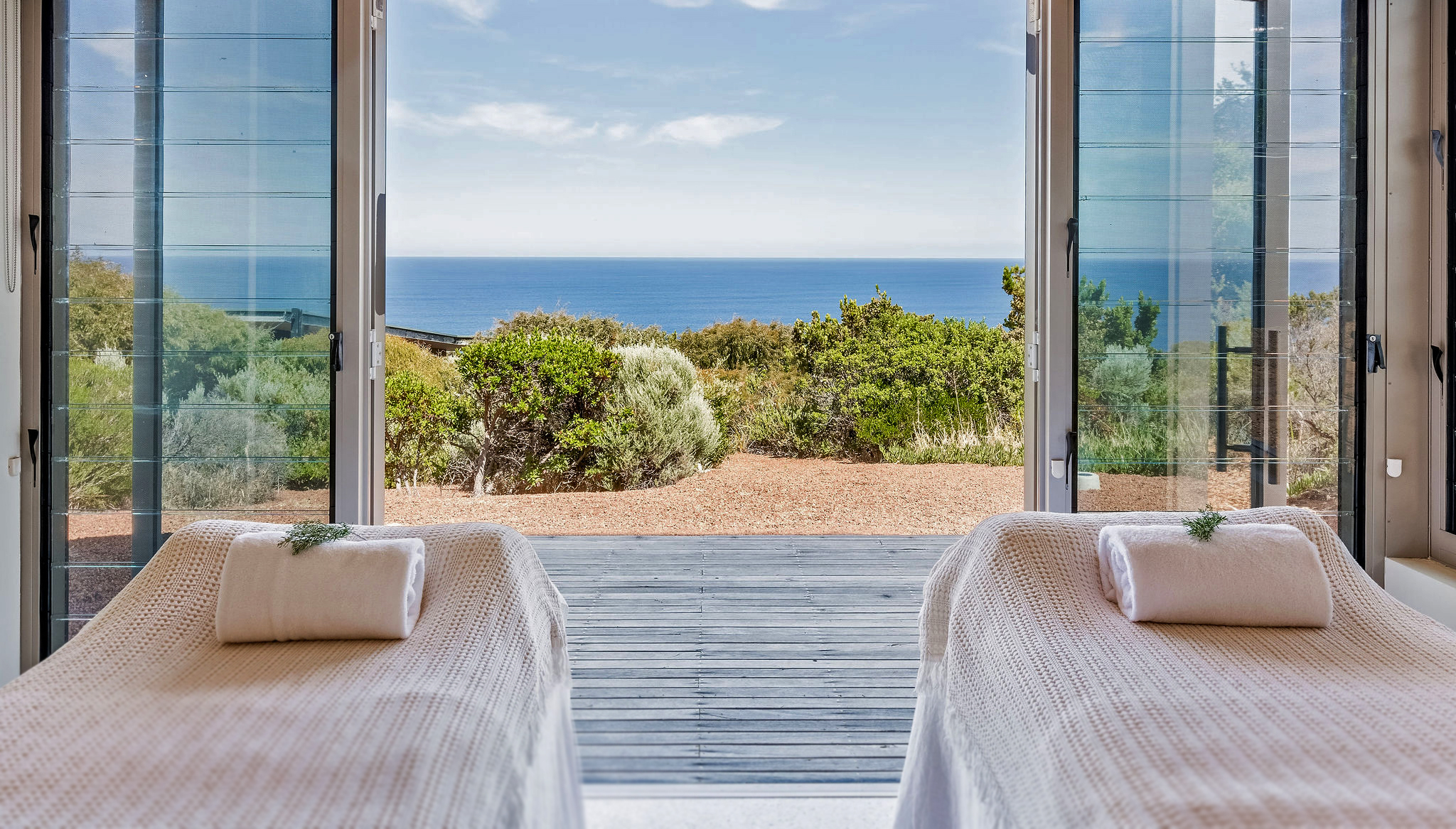 Twin treatment beds facing the ocean through open glass doors at Injidup Spa Retreat's day spa