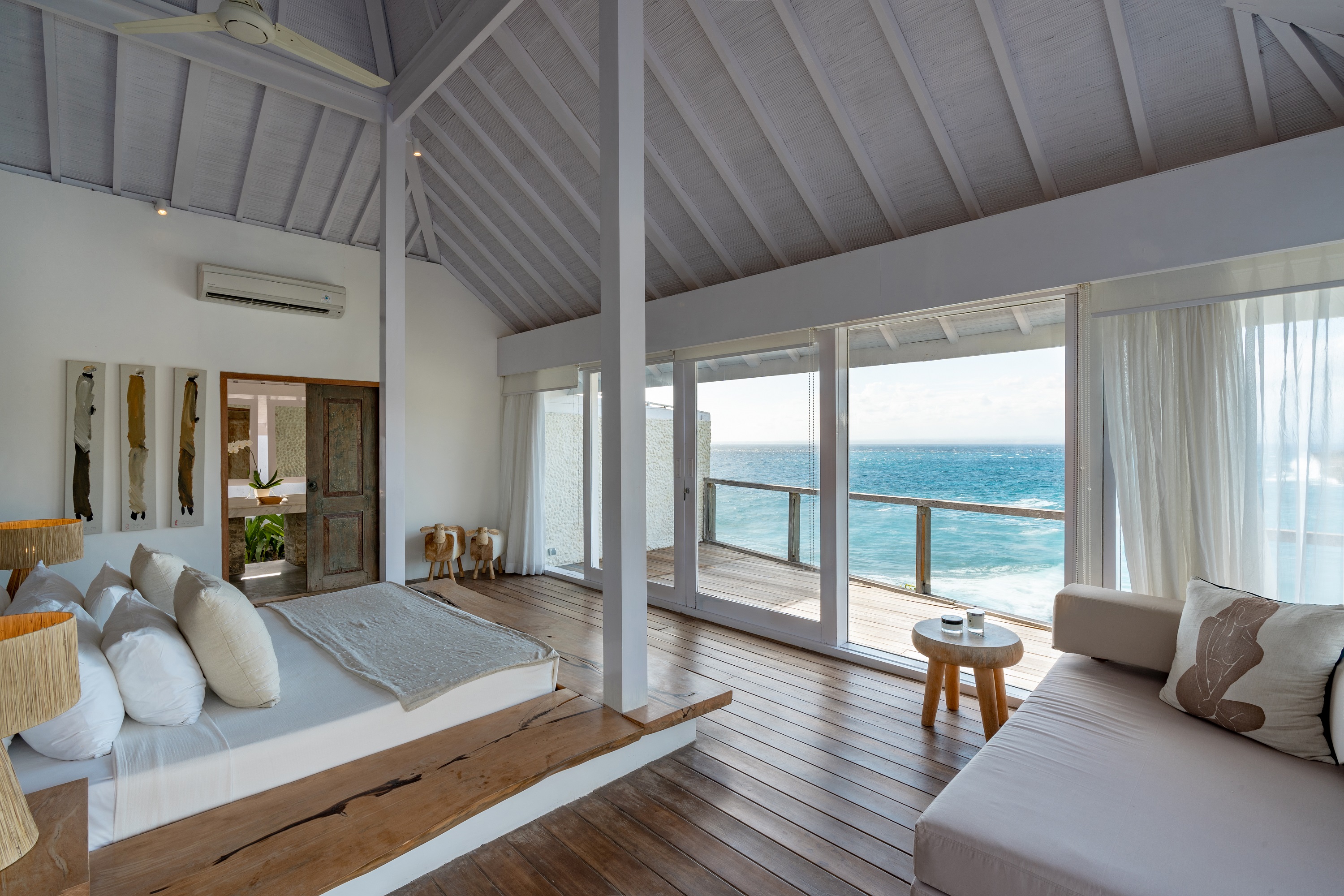 Master bedroom at Villa Tranquilla — floor-to-ceiling glass doors opening directly to the ocean