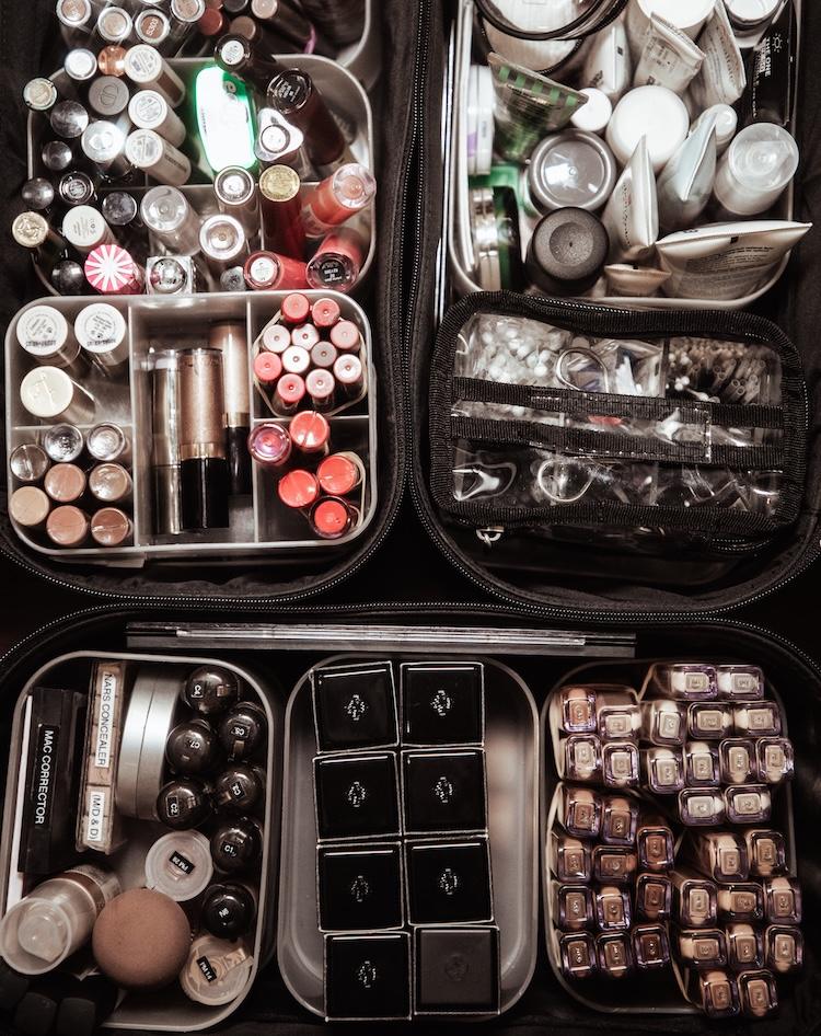 Close-up of hands dipping a fine makeup brush into a small pot of dark gel liner