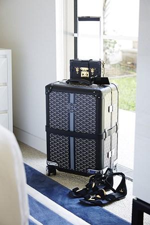 A MONOGRAMMED MAISON GOYARD SUITCASE SITS PRETTY IN ROXY’S BEDROOM