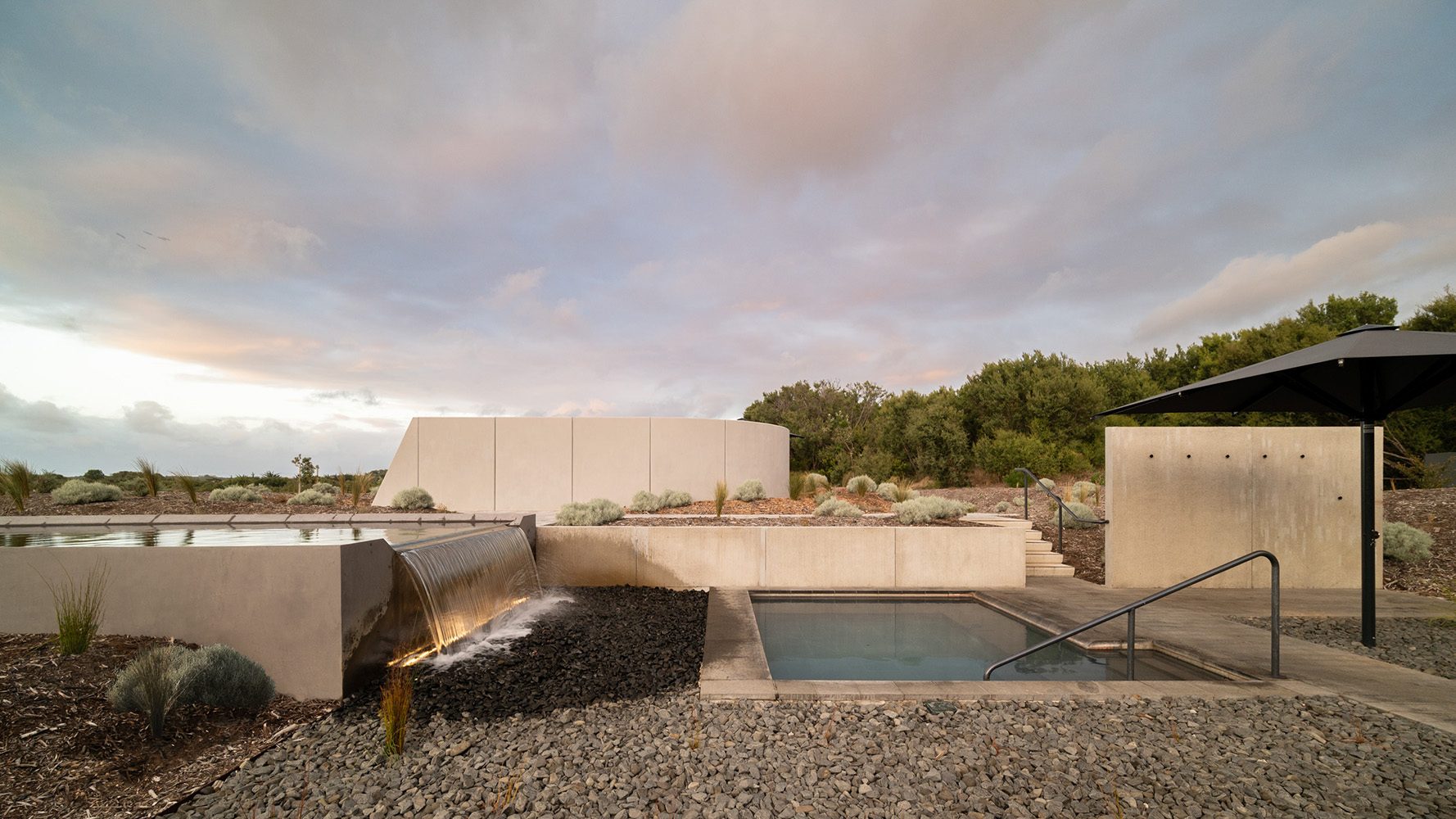 A waterfall spilling into a plunge pool under a pink dusk sky at Alba Thermal Springs