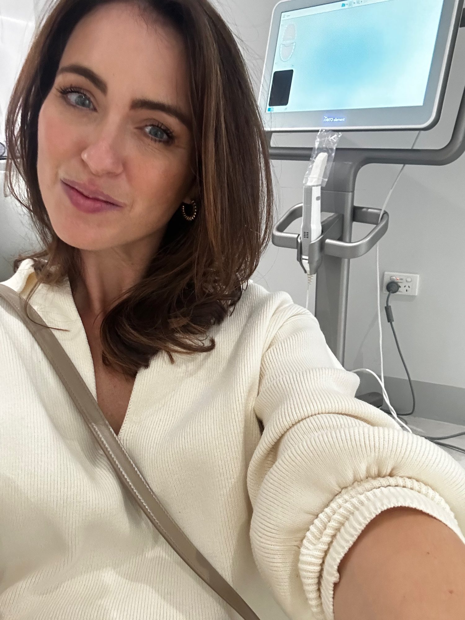 Sigourney Cantelo taking a selfie in a clinic room beside a medical scanner