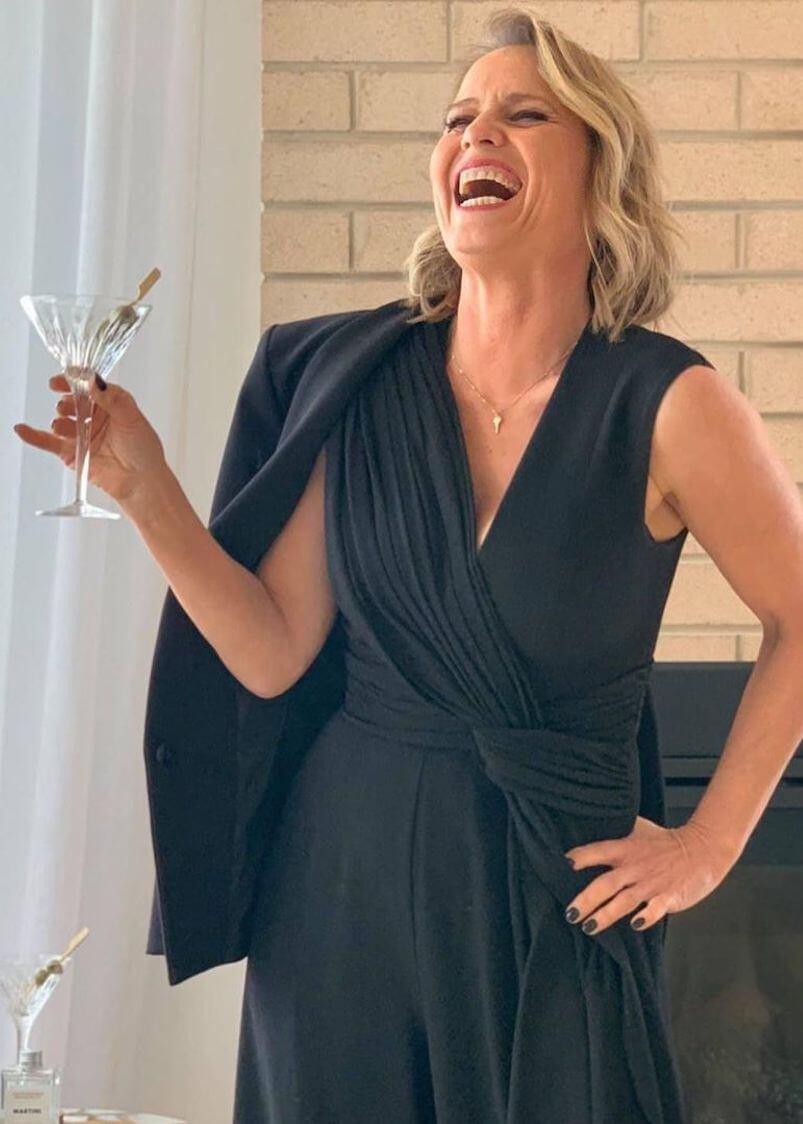 Close-up selfie of Shaynna Blaze wearing rose gold dragonfly necklace and bracelet against navy backdrop